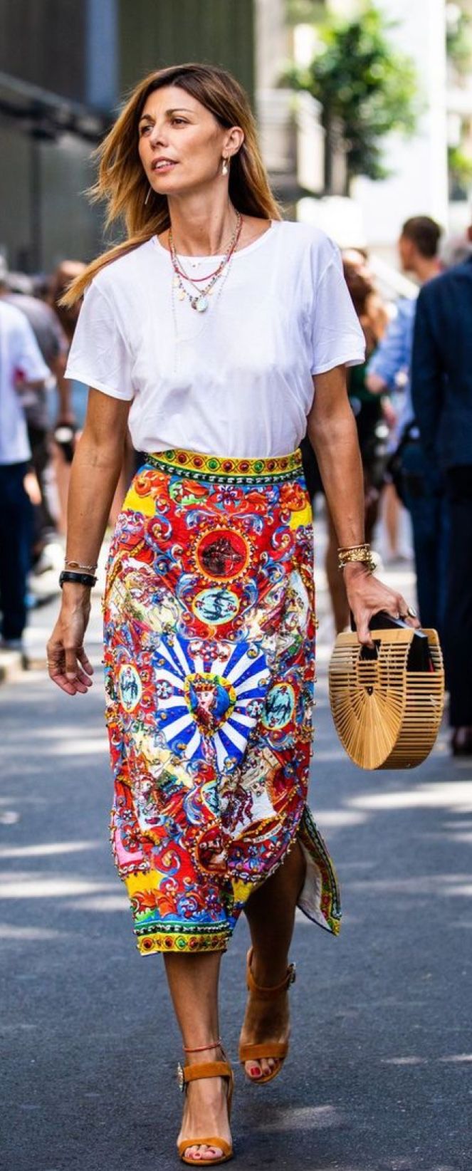 White tee with bold multicolor printed midi skirt and wicker bag on city street