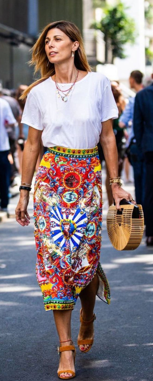 White tee with bold multicolor printed midi skirt and wicker bag on city street