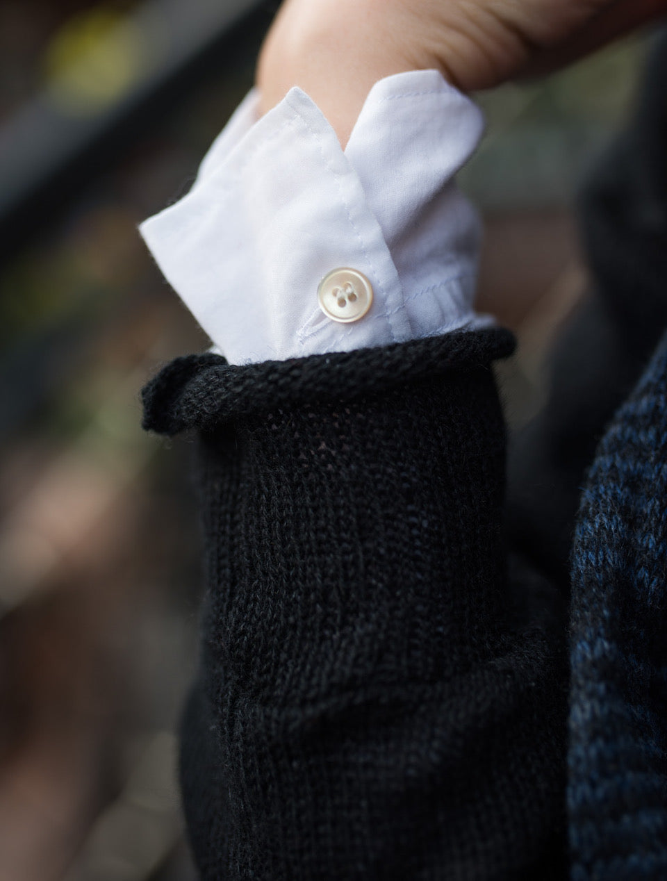 White cotton shirt cuff layered under a sweater, demonstrating intentional shirt layering