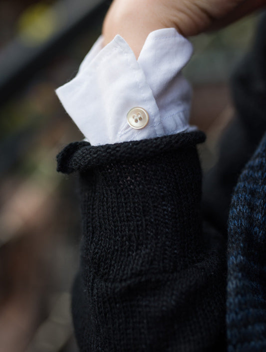 White cotton shirt cuff layered under a sweater, demonstrating intentional shirt layering