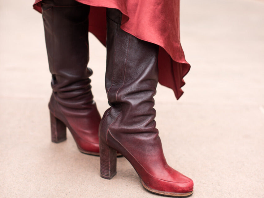 Burgundy knee-high boots styled with a flowing skirt in an urban setting