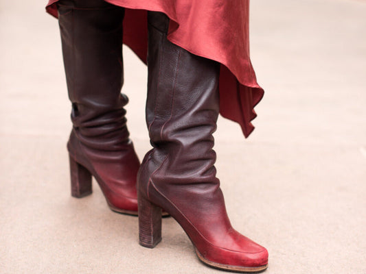 Burgundy knee-high boots styled with a flowing skirt in an urban setting